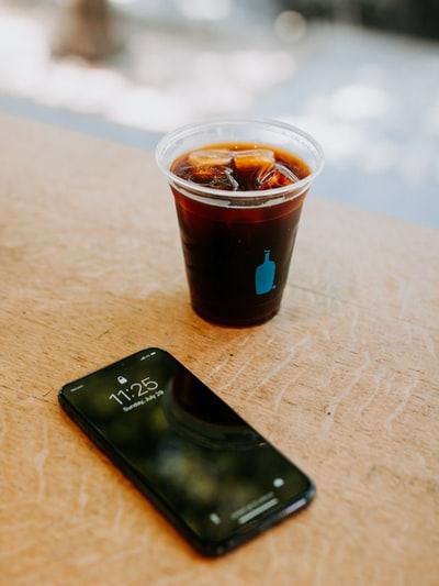 黑色iPhone 7旁边清楚一次性杯装满冰块的饮料
